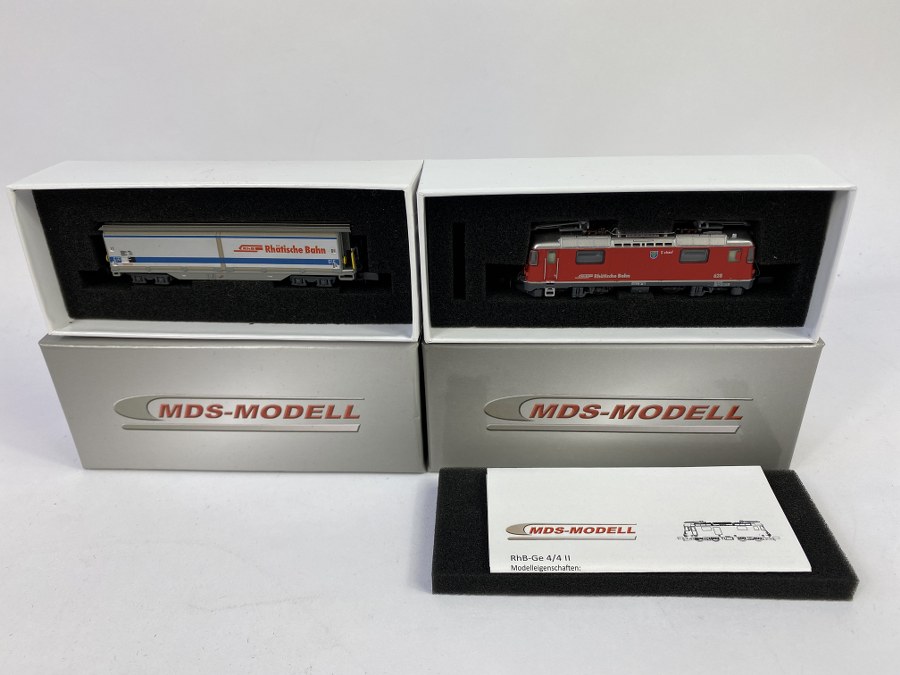 MDS MODELL, Écartement N – Lot de 2 éléments dont : - locomotive électrique type Ge 4/4 II, RhB, 628, rouge, - Wagon fourgon à portes coulissante, RhB. Gris argent à bandes bleue. Réf 60000, 61002. NB