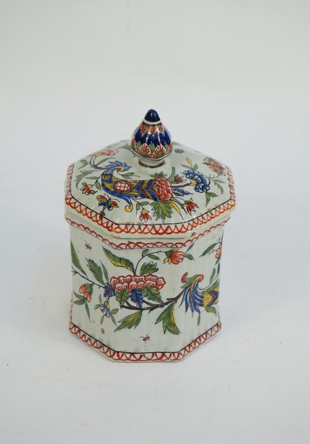 Pot couvert à panse facettée en faïence fine de Rouen à décor polychrome de cornes d'abondance fleuries. Égrenures et restaurations (prise recollée). H. : 18 cm.