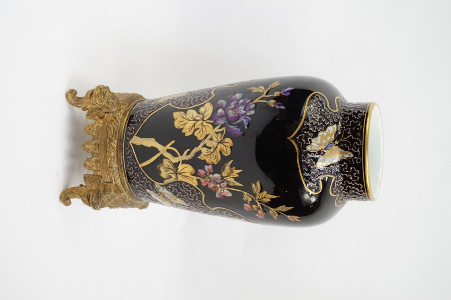 Vase en porcelaine chinoise monté en bronze. Porcelaine à couverte noire à motif réticulé en relief et décor peint de pivoines et papillons. Début du XXe siècle. H. : 32,5 cm.