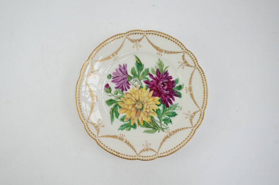 Assiette en porcelaine à décor de chrysanthèmes peint à la main, signé V.B. daté 83. 21 cm de diamètre.