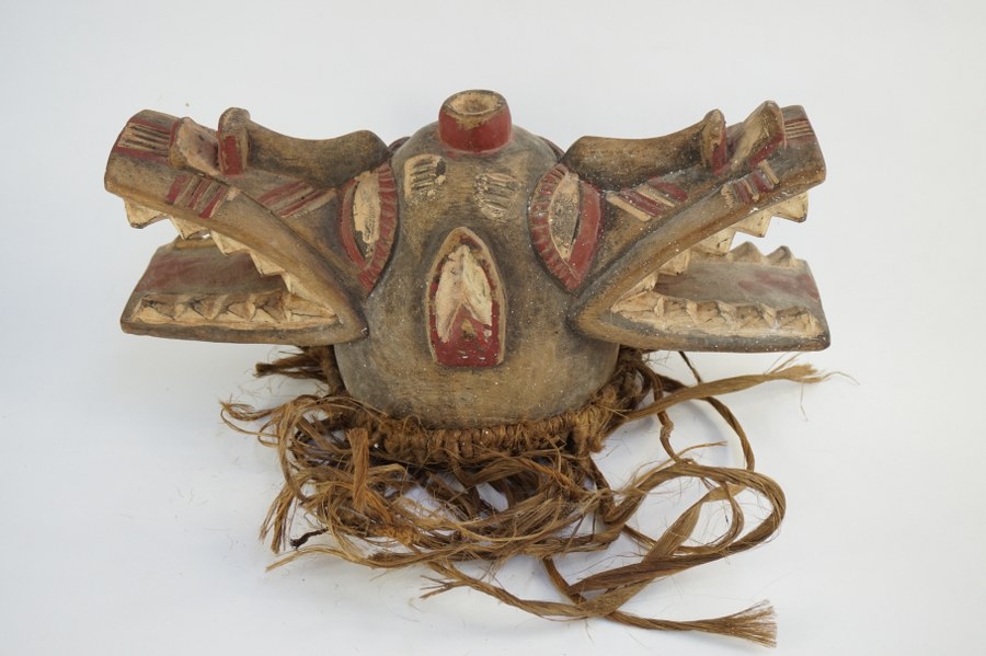 Heaume cracheur de feu Wambêlê SÉNOUFO représentant un animal fantastique bicéphale composite. Bois sculpté polychrome et fibres végétales. XXe siècle. Côte d'Ivoire.