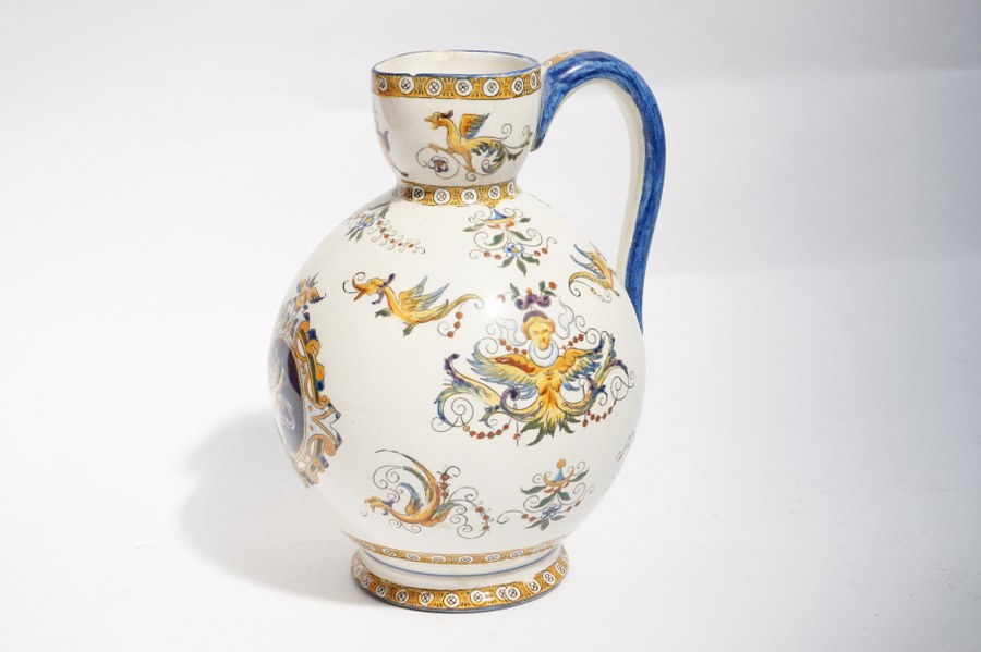 Cruche en faïence de GIEN à décor de Florentine, marqué sous la base GIEN et KH. Vers 1900. H. : 29 cm. Égrenures sur la lèvre.