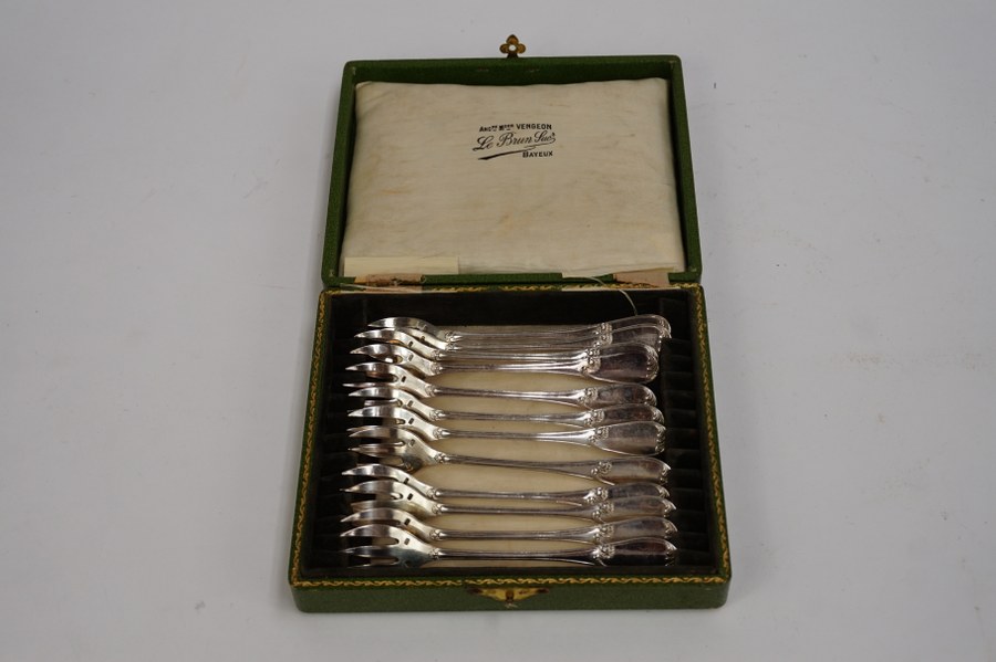 Douze fourchettes à huître modèle de style Rocaille en métal argenté dans leur écrin de bois cartonné vert.