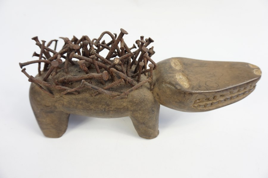 Fétiche à clous NKISI représentant un chien stylisé à tête unique. Bois sculpté patiné et métal. XXe siècle. République démocratique du Congo.
