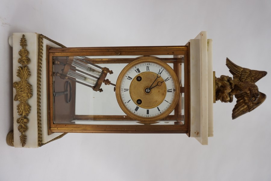 Pendule cage en verre, bronze doré et marbre blanc. Décorée d'un aigle, balancier au mercure. XIXe siècle. H : 43 cm.