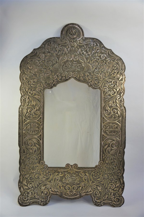 Miroir en laiton repoussé à décor de fleurs. H : 105 cm.